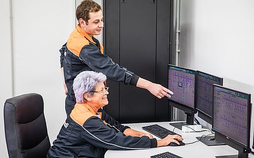 Two workers in Mondi uniform looking at a computer monitor